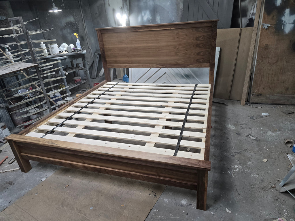 Angled workshop view of walnut platform bed with exposed slats