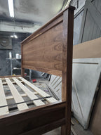 Close view of walnut bed headboard side, wood grain and frame joint in the workshop