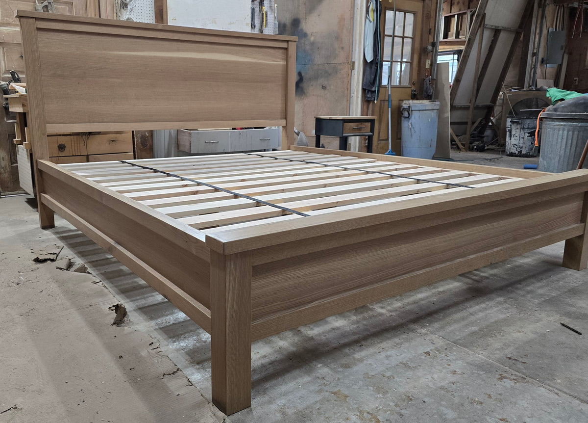 White oak platform bed with exposed slats and panel headboard in the workshop