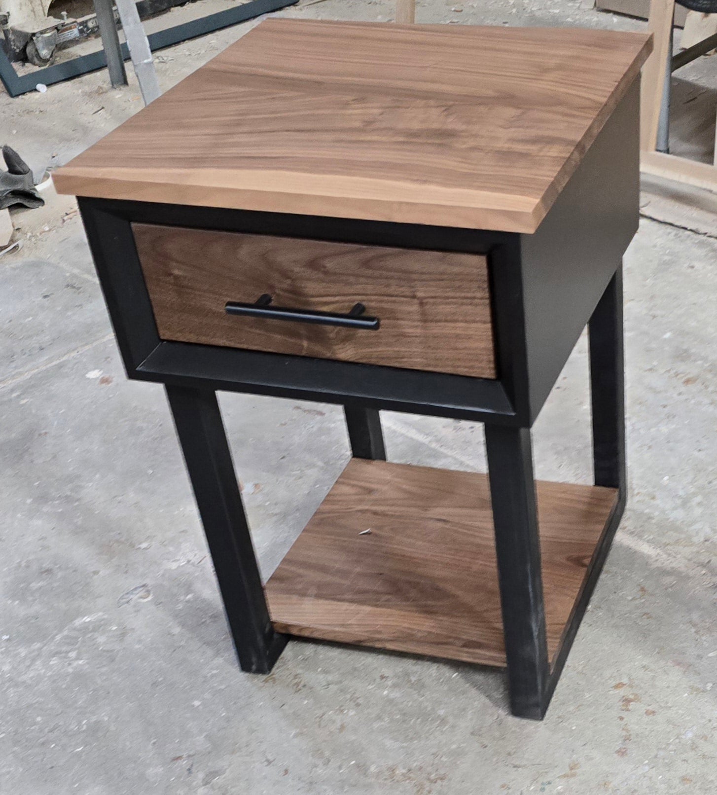 Modern Black and walnut nightstand with drawer and shelf on steel legs.