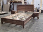Walnut platform bed viewed diagonally from the foot with two nightstands behind