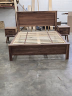 Full-length front view of walnut bed with slats and two nearby nightstands