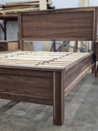 Walnut bed viewed from the footboard corner with slats exposed