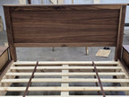 Front close-up of walnut panel headboard and bed slats