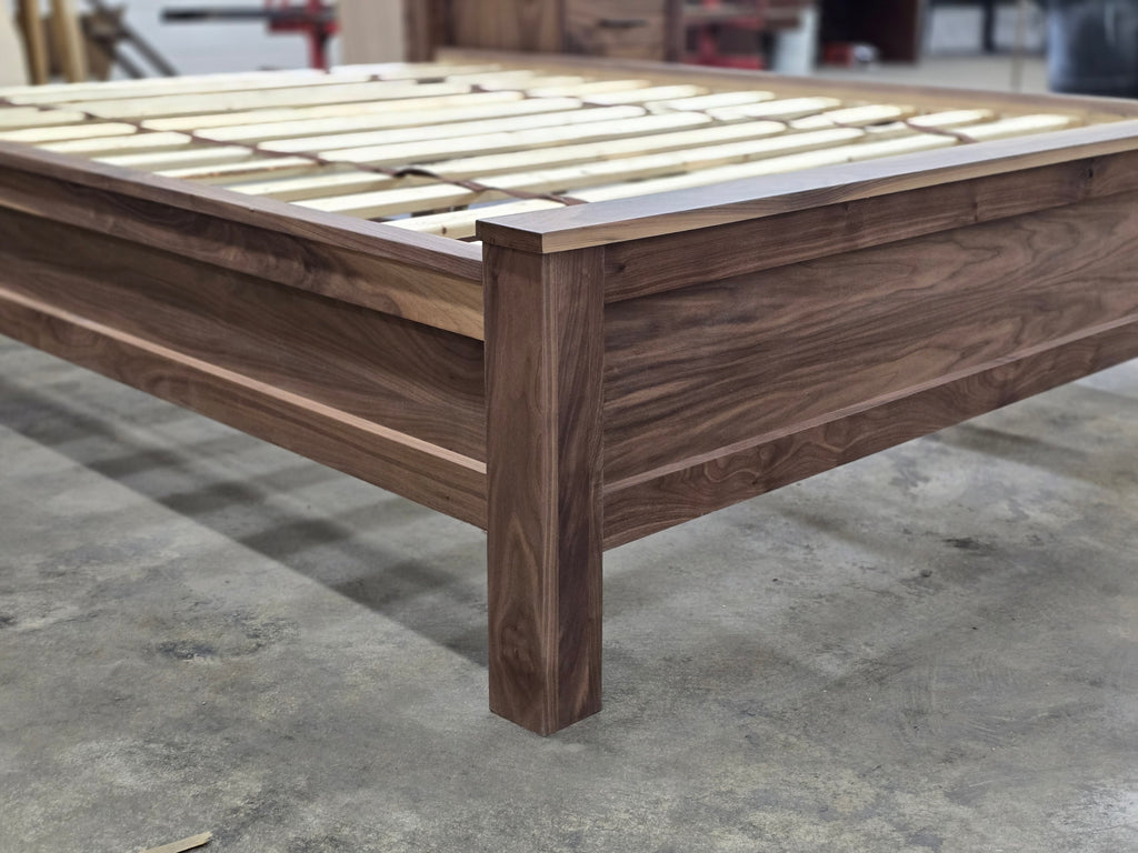 Close-up of walnut footboard corner, leg and exposed bed slats