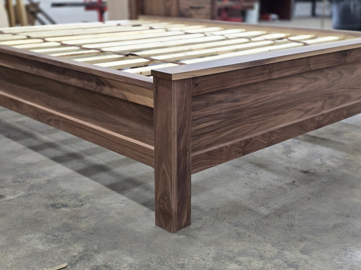 Close-up of walnut footboard corner, leg and exposed bed slats