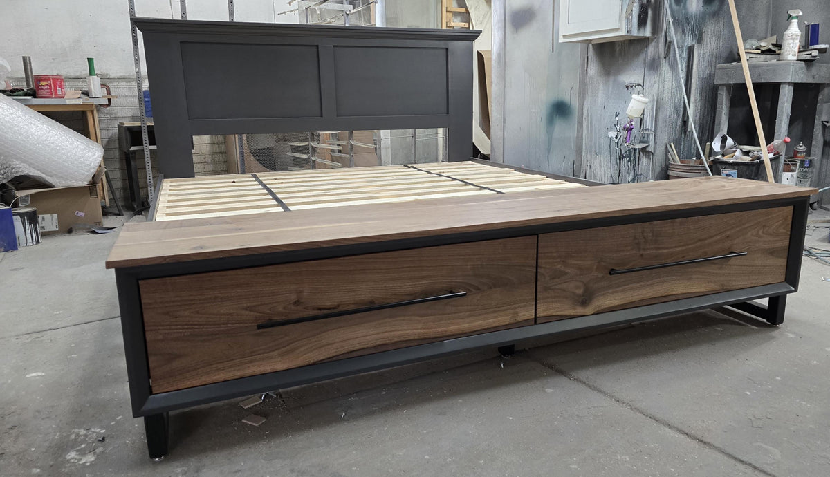 Storage-bed footboard with two wood-grain drawer fronts and dark handles in the workshop