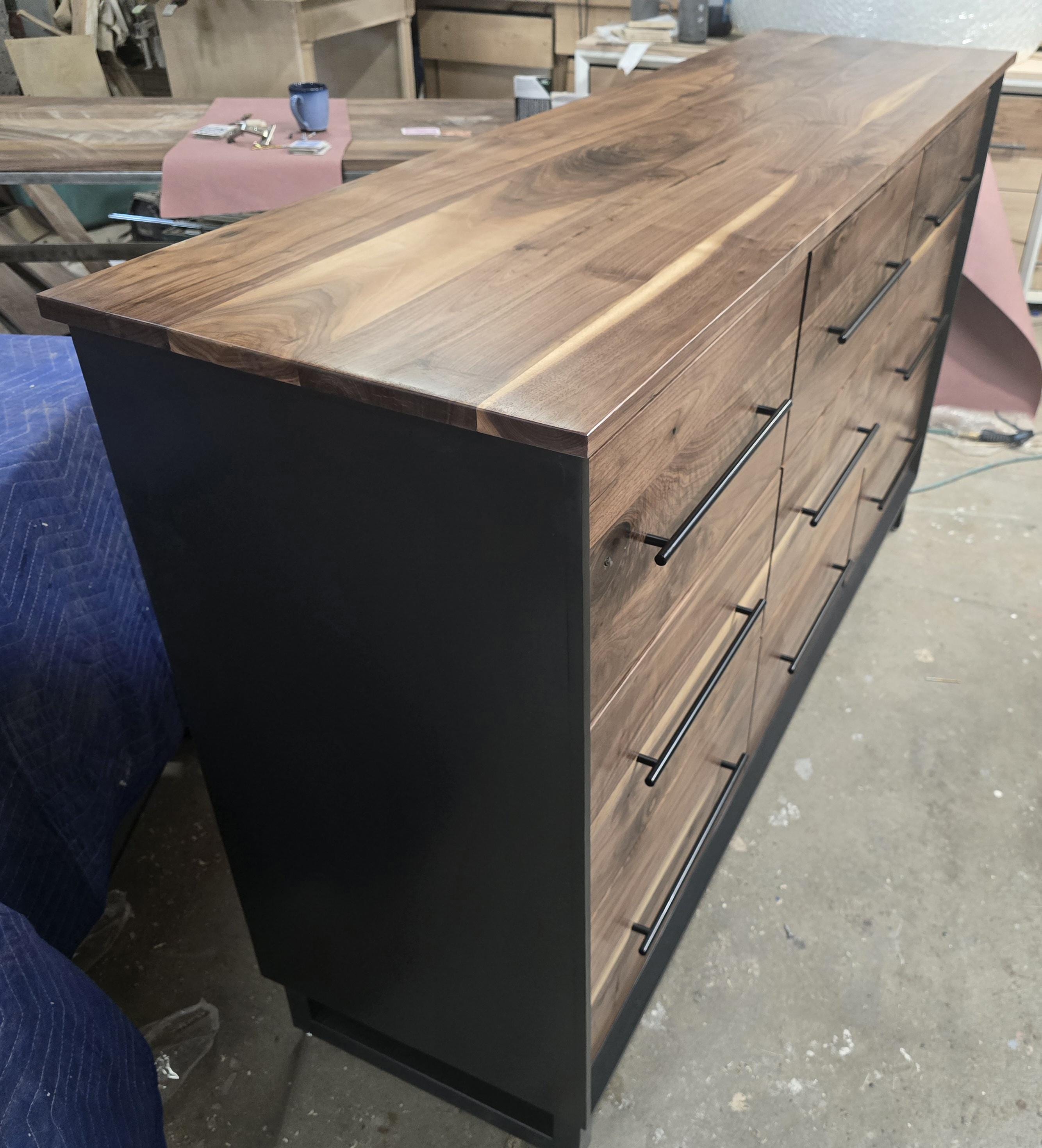 6foot 9 drawer walnut faced modern dresser in black with solid walnut top on steel legs.